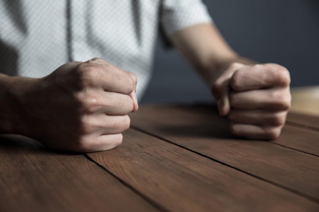 Hombre enojado puños sobre la mesa