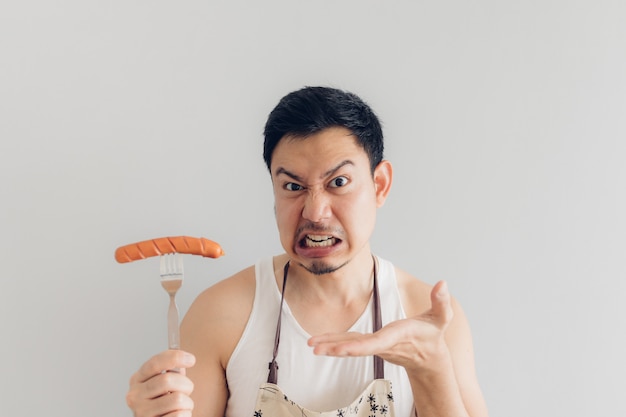 Foto el hombre está enojado con la salchicha, ya que no es lo que esperaba para su dieta o no es delicioso.