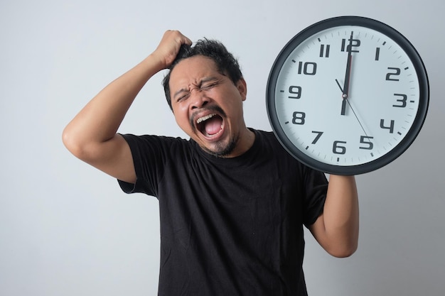 El hombre enojado tira de su cabello mientras sostiene el reloj