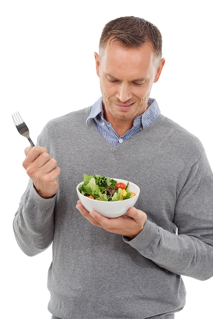 Hombre con ensalada frunciendo el ceño en la cara y problema vegetal con un estilo de vida saludable y una dieta aislada en el fondo blanco Bienestar de la salud y hombre con dudas sobre la nutrición de la elección de alimentos en el estudio