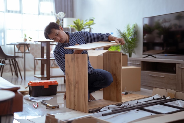 Hombre ensamblando muebles que compró en línea