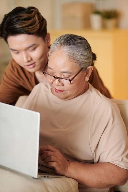 Hombre enseñando a la abuela a trabajar en la computadora