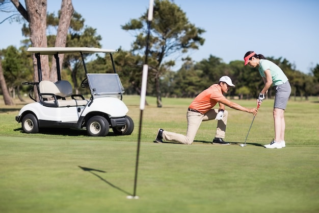 Hombre enseñando a mujer jugando al golf