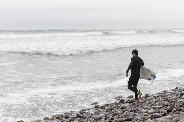 Hombre entrando al agua para surfear