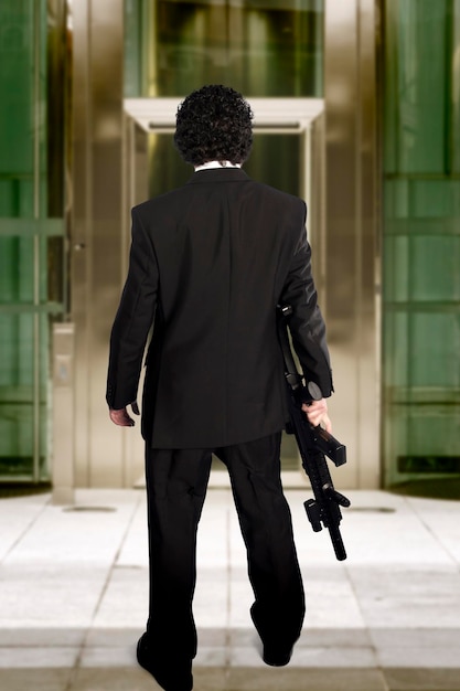 Foto hombre entrando a un edificio comercial con una ametralladora