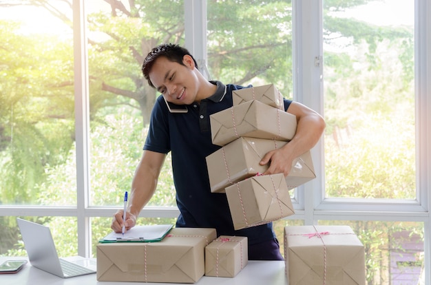 Hombre de entrega asiático joven hermoso feliz después de la nueva orden del cliente