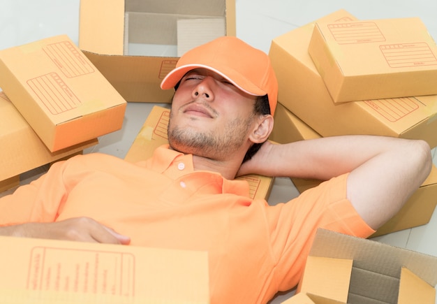 El hombre de entrega se relaja tomando una siesta en cajas