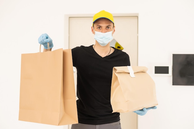 Hombre de entrega sosteniendo cajas de cartón en guantes de goma médicos y máscara. Espacio de copia. Entrega rápida y gratuita. Compras en línea y entrega expresa. Cuarentena.