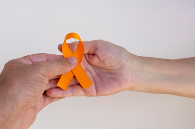 Foto hombre entregando cinta naranja a mujer. campaña para prevenir el cáncer de piel, melanoma, diciembre naranja