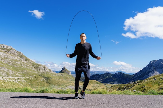 Un hombre entrena resistencia antes de las competiciones saltando la cuerda Entrenamiento de montaña en verano