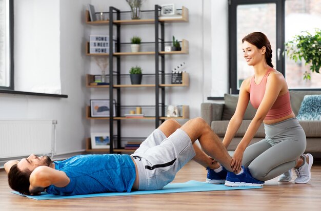 hombre con entrenador personal haciendo abdominales en casa