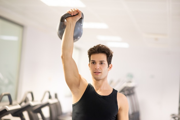 Hombre entrenando en un gimnasio con pesas rusas