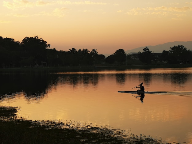 El hombre entrenando kayak navega en el río atardecer.