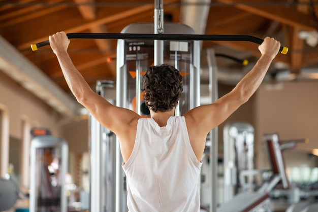 Hombre entrenando sus hombros y espalda en un gimnasio