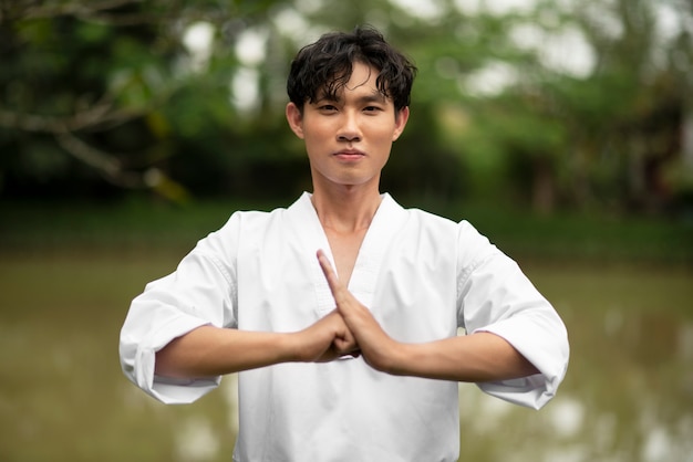 Foto hombre entrenando en taekwondo al aire libre en la naturaleza