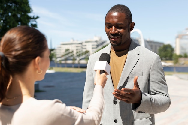 Foto hombre entrevistado por periodistas al aire libre