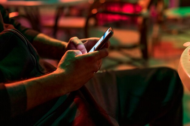 Hombre enviando mensajes de texto por teléfono en el club