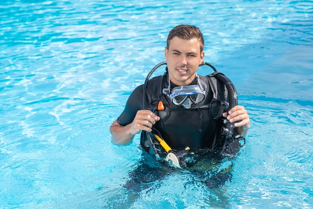 Hombre en equipo de buceo está entrenando en la piscina