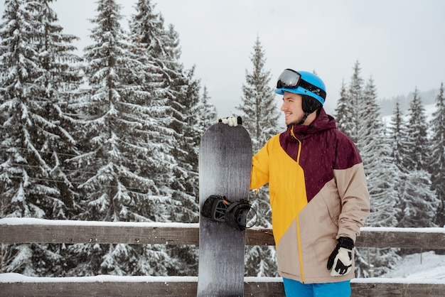 El hombre en el equipo de esquí, con gafas de seguridad, está parado contra la montaña y los árboles. Deportes de invierno y recreación, actividades de ocio al aire libre.