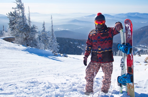 Un hombre con equipo de snowboard en la cima de una montaña.