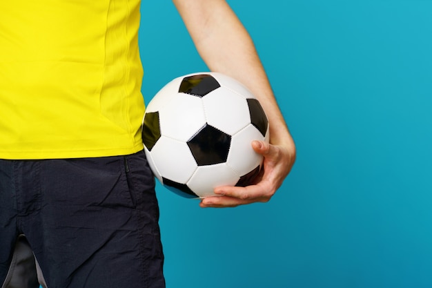 El hombre es fanático del fútbol en camiseta amarilla con balón de fútbol en azul