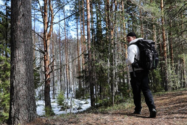 Un hombre es un turista en un pinar con una mochila. Un viaje de senderismo por el bosque. Reserva de pinos para paseos turísticos. Un joven en una caminata en la primavera.