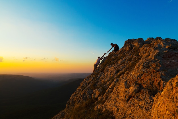 Hombre escalada con otro hombre ayudando