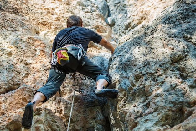 Hombre escalando en roca contra el fondo de cielo azul