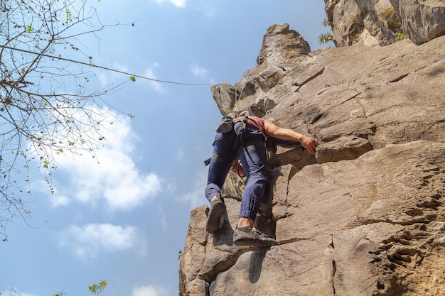 Hombre escalando en roca mientras busca la cumbre