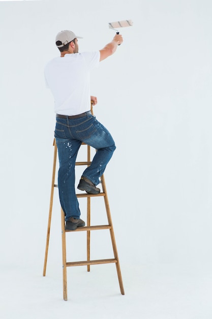 Hombre en escalera pintando con rodillo