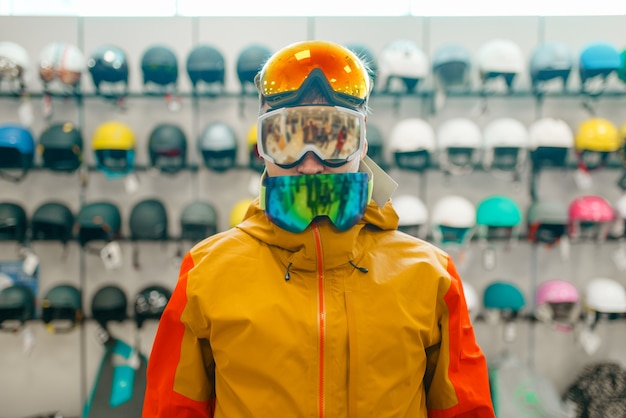 Foto hombre en el escaparate probándose tres máscaras para esquiar o hacer snowboard, vista frontal, compras en tienda de deportes. estilo de vida extremo de la temporada de invierno, tienda de ocio activo, compradores que eligen proteger el equipo