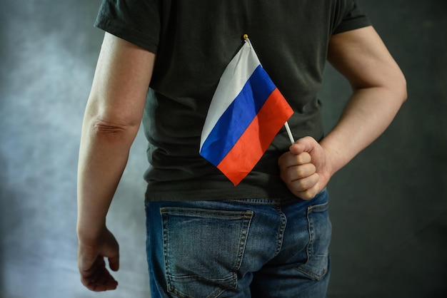 Hombre escondiendo la bandera rusa a sus espaldas