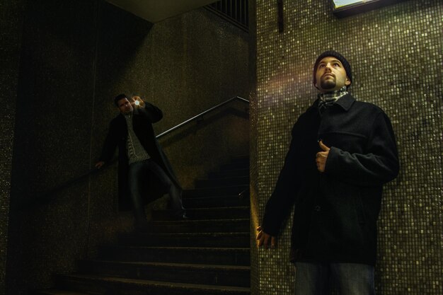 Foto hombre escondiéndose contra la pared en el metro oscuro