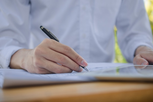 El hombre escribe en el documento de negocios que trabaja en casa, concepto de la FMH que trabaja en casa y se queda en casa preventivo del virus Corona 2019