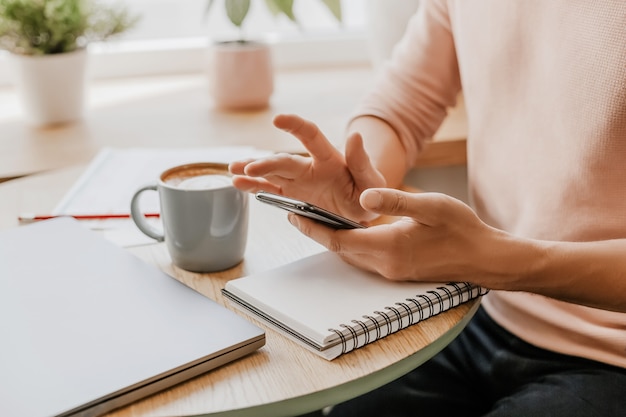 El hombre escribe información empresarial en un cuaderno en el lugar de trabajo en la oficina con el teléfono inteligente