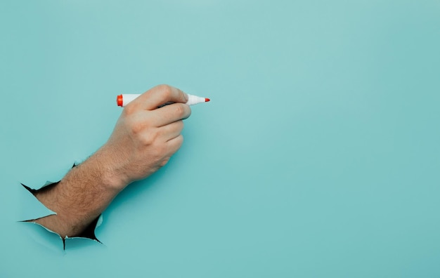 Un hombre escribe un marcador en una pared de papel azul roto