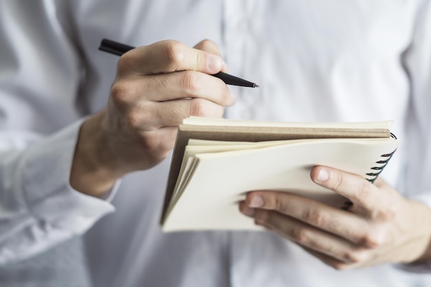 El hombre escribe de pie con un bolígrafo en el diario en una oficina soleada concepto de educación y negocios Cerrar