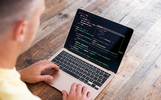 Hombre escribiendo código de computadora en una computadora portátil