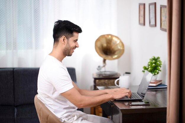 Foto hombre escribiendo en la computadora portátil mientras habla por video con su amigo