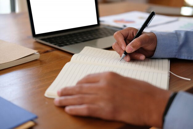 Foto hombre escribiendo una nota en el cuaderno, empresario trabajando organizando el plan en el lugar de trabajo