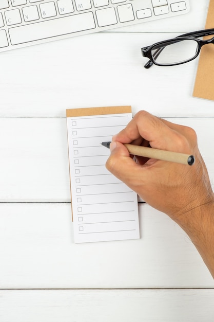 Foto un hombre está escribiendo en papel de lista de tareas