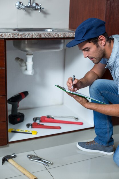 Hombre escribiendo en portapapeles con herramientas de trabajo