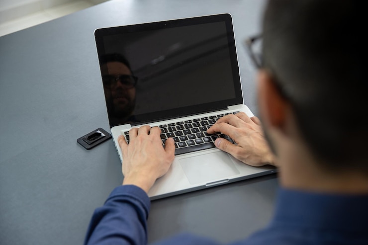 Foto un hombre escribiendo en su cuaderno en el escritorio de su oficina