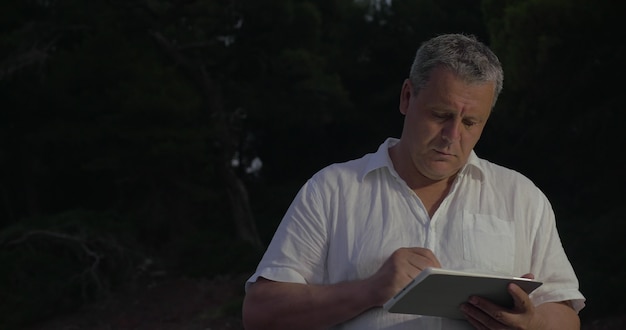 Hombre escribiendo en tableta en crepúsculo