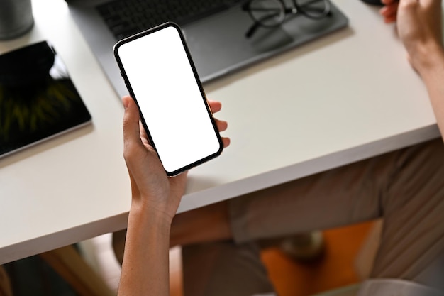 Un hombre en el escritorio de su oficina usando un teléfono inteligente Maqueta de pantalla blanca de teléfono celular