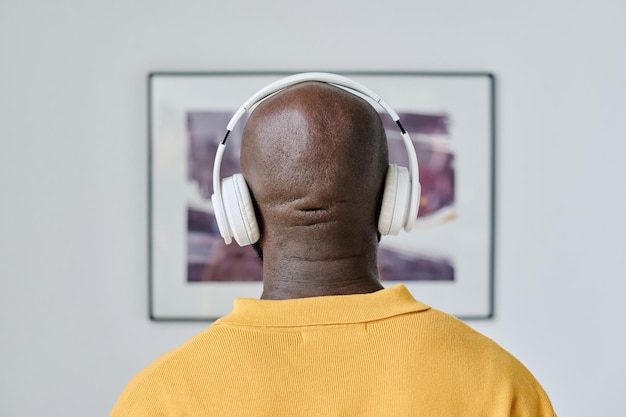 Hombre escuchando guía en auriculares en galería