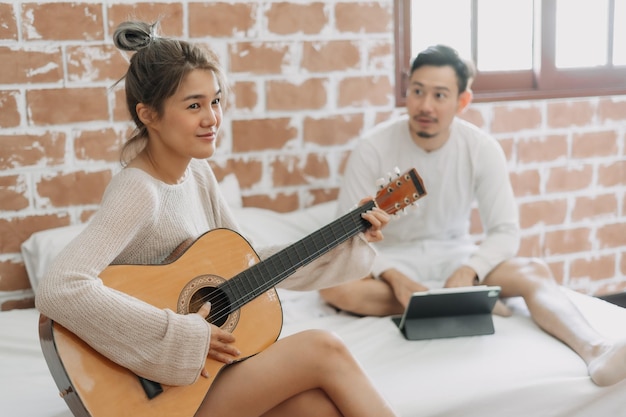 Hombre escuchando a su novia tocar la guitarra en un buen fin de semana de pasatiempo