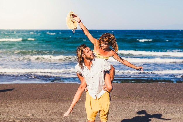 Foto hombre a espaldas de mujer alegre en la playa contra el cielo