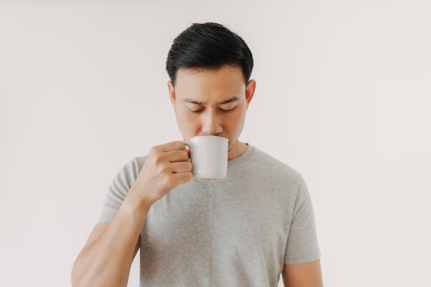 El hombre está bebiendo café o té aislado sobre fondo blanco.