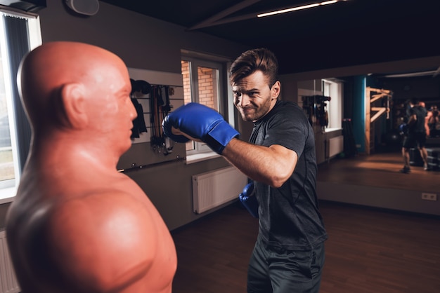 Un hombre está boxeando en el gimnasio. Él lleva un estilo de vida saludable.